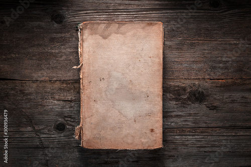 Closed book on vintage wooden background.  Old book on the wooden table. Closed book with empty cover laying on wooden table. photo