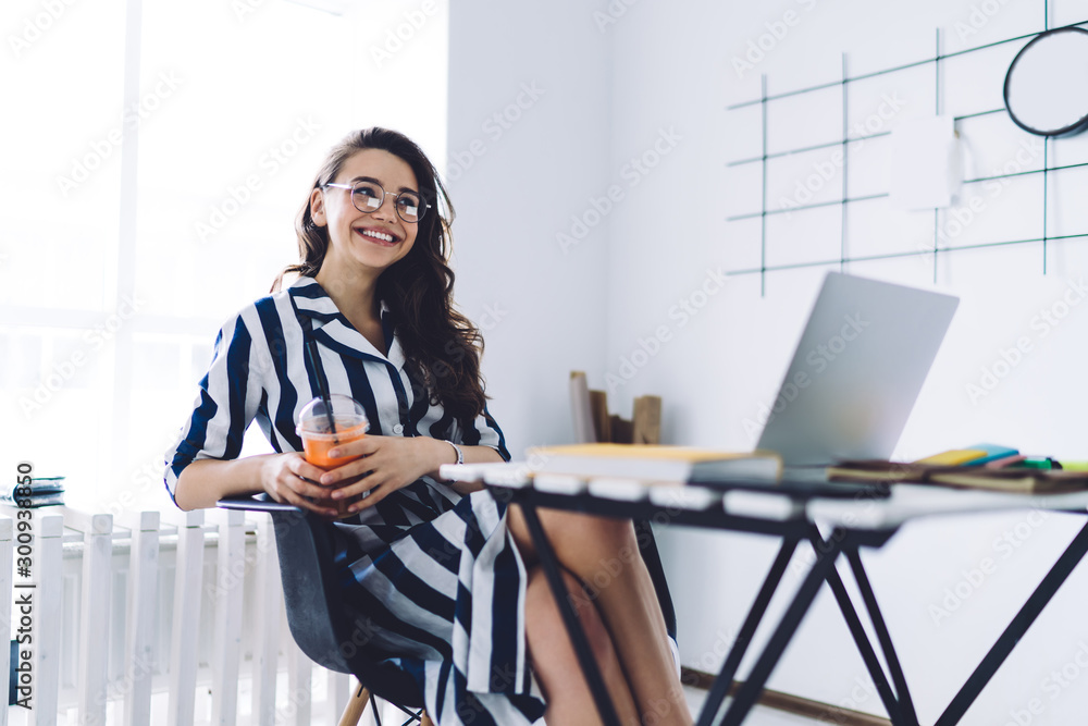 Smiling woman with orange juice taking break at workplace Smiling woman with orange juice taking break at workplace