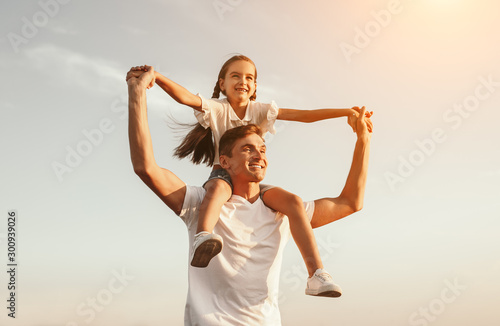 Cheerful father carrying daughter on shoulders