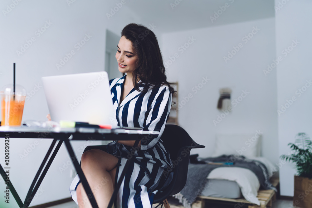 Elegant woman writing while sitting at desk and using laptop at home Elegant woman writing while sitting at desk and using laptop at home