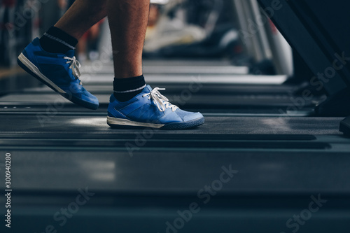 close up of man feet running on treadmill in the gym. concept of doing sport, healthy living, weight loss. © mlasaimages