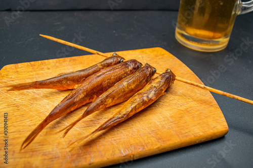 Dried mullet on a wooden Board with a mug of beer on the table. Fish and seafood cuisine. Tasty snack. photo