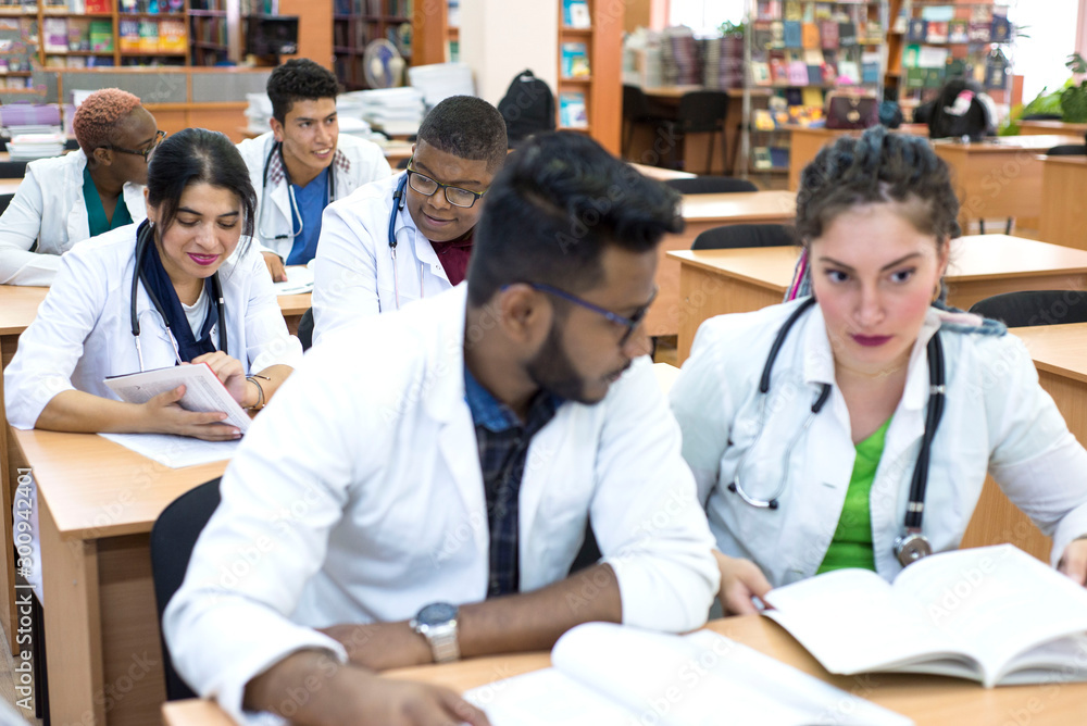 a multinational group of medical students, sitting at the table, studying medical literature a multinational group of medical students, sitting at the table, studying medical literature