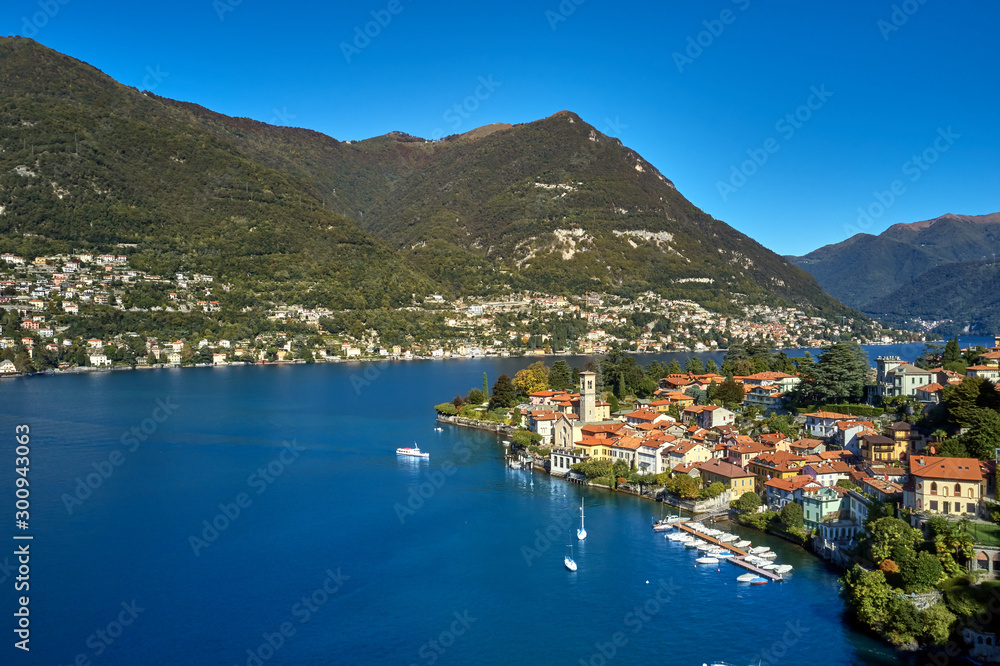 Panoramic top view of Lake Como. Lombardy, Italy. The small town of Torno. Autumn season. Perfect clear blue sky. Boats parked off the coast