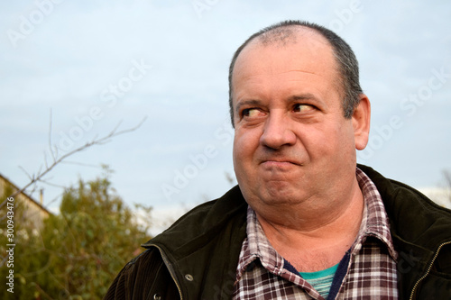 Portrait of an adult man with a cunning  facial expression. A man has a funny face. The man is kind and positive. Caucasian, close up.