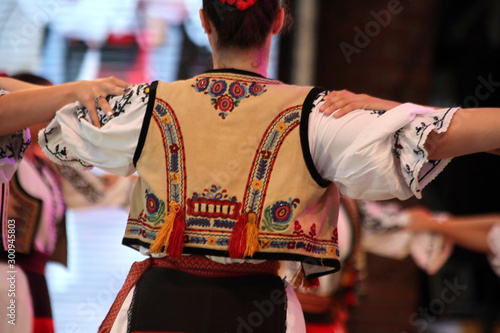 Dancers hold hands in a traditional Romanian dance wearing traditional beautiful costumes.