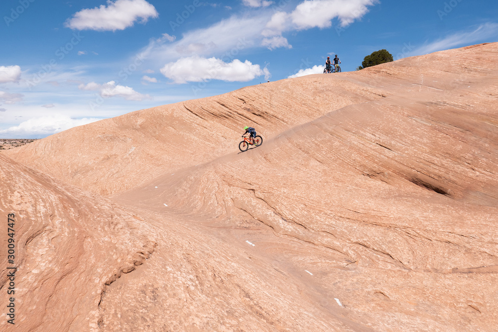 Son, mother and grandfather riding mountain bikes of singletrack in Moab, Utah