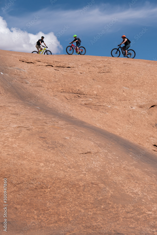 Son, mother and grandfather riding mountain bikes of singletrack in Moab, Utah