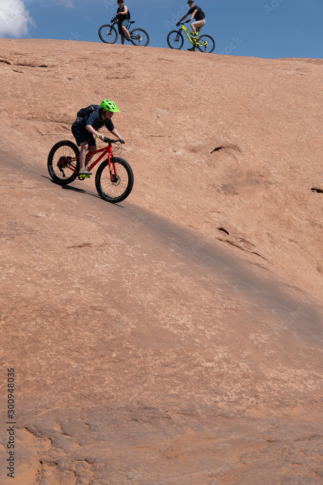 Son, mother and grandfather riding mountain bikes of singletrack in Moab, Utah