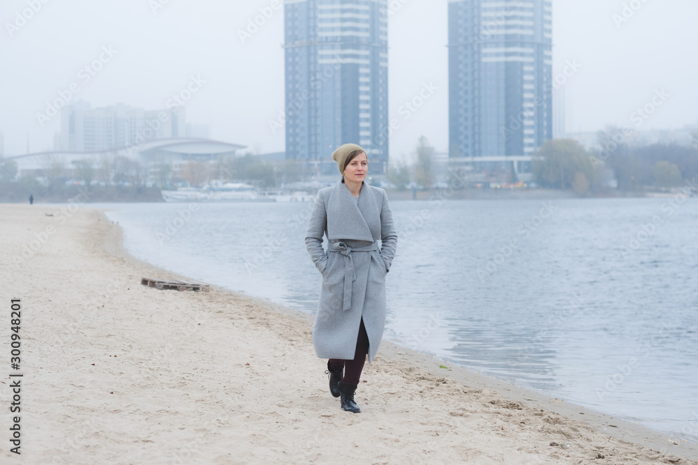 Young woman walking away alone wearing a grey overcoat Young woman walking away alone wearing a grey overcoat
