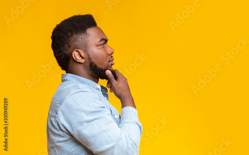 Profile portrait of thoughtful african american guy over yellow background photo