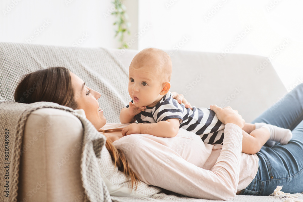 Funny little baby bonding with mom, lying on couch together Funny little baby bonding with mom, lying on couch together