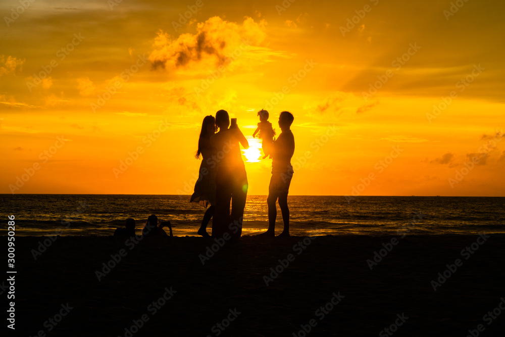 mother and father carry a child to take a photo on the beach in golden sunset.