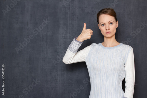 Portrait of serious concentrated girl showing thumb up gesture