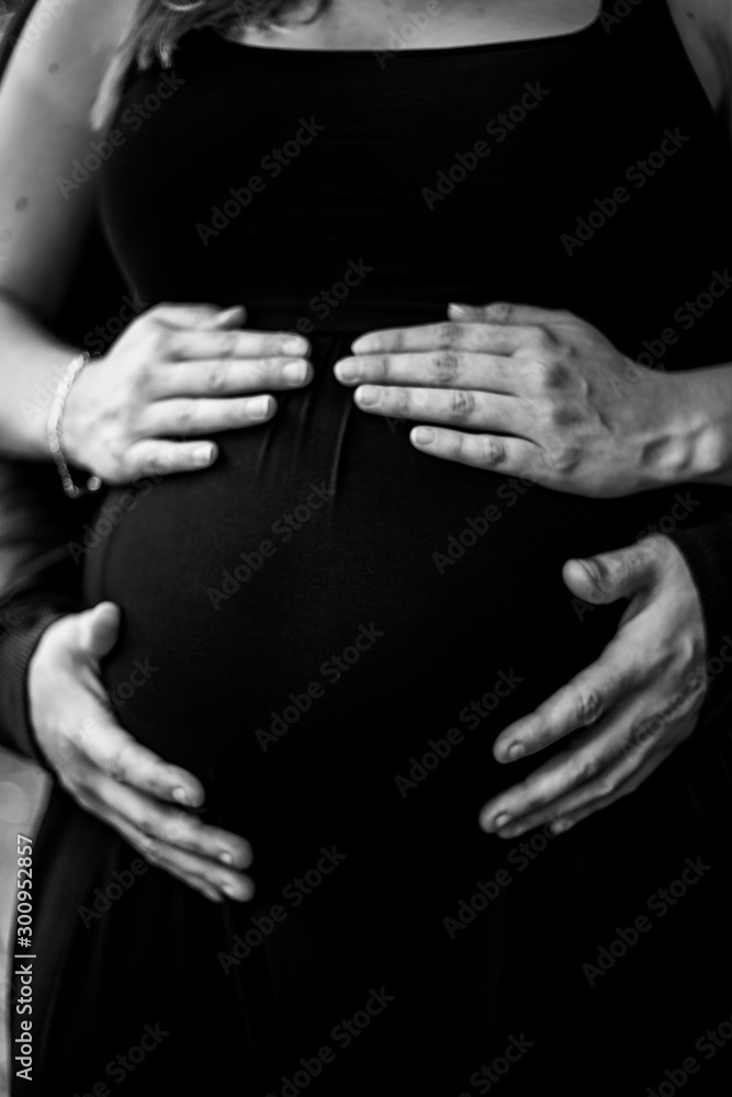 hands of a man and woman holding pregnant belly