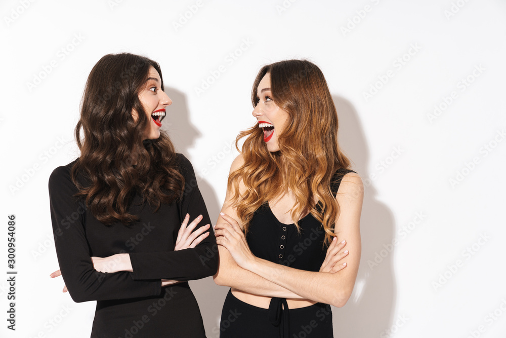 Image of young women in black outfit smiling and looking at each other Image of young women in black outfit smiling and looking at each other