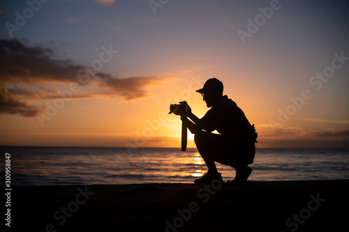 The silhouette of a male hobbyist photographer taking photos of a beautiful colorful sunset on the West Puerto Rico coast near Rincon