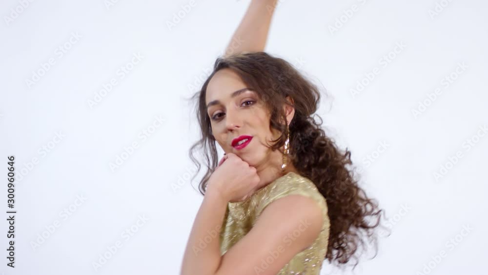 Portrait shot of happy young woman wearing sparkly dress and gold earrings looking at camera and dancing isolated on white background Portrait shot of happy young woman wearing sparkly dress and gold earrings looking at camera and dancing isolated on white background
