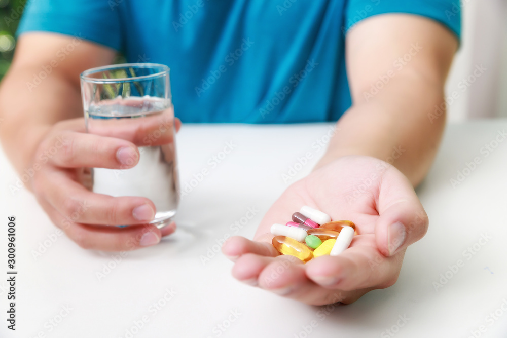Close up of Colorful pills, capsule medicines and glass of water in man's hands. Medical and Health care or illness concept. Close up of Colorful pills, capsule medicines and glass of water in man's hands. Medical and Health care or illness concept.