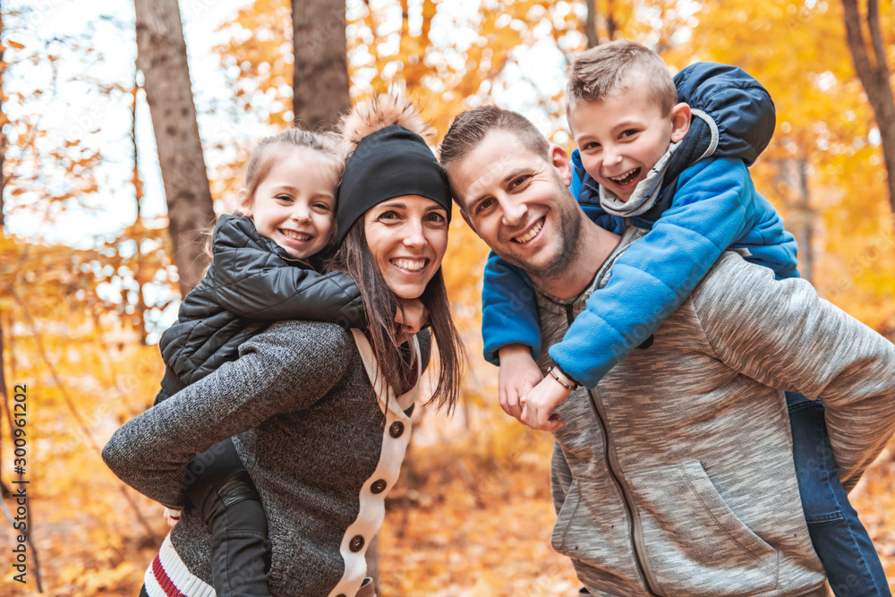 A portrait of a young family in the autumn park - obrazy, fototapety, plakaty 