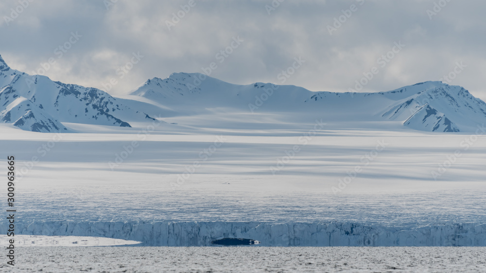 Snow covered mountains and a glacier by an arctic fjord in Svalbard