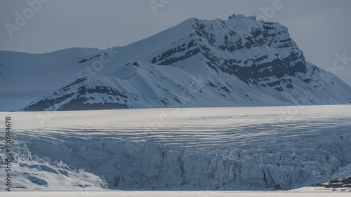 Cracking glacier with crevasses in the ice and mountains in the background © Jani Katajisto