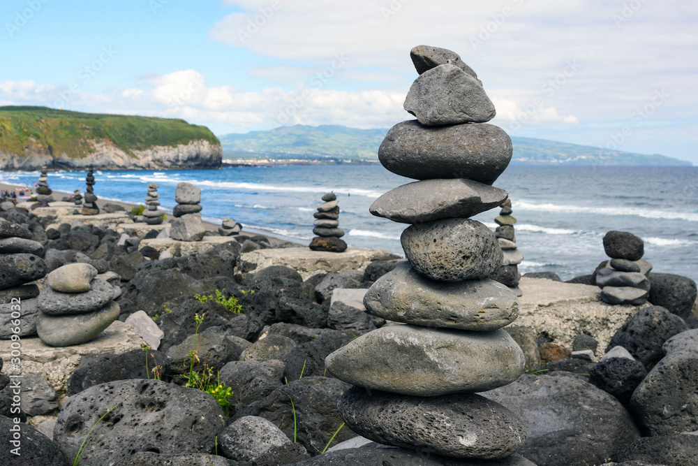 Obraz premium Stack of zen stones on beach.Cairns on the beautiful sea beach of Praia do Areal de Santa Barbara, island of San Miguel, Azores, Portugal.