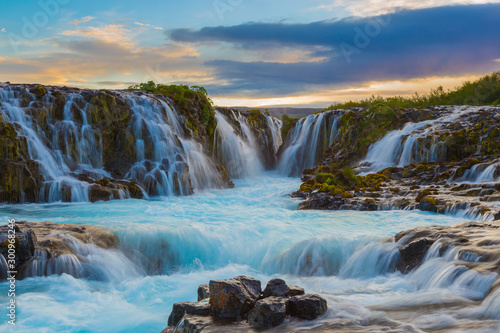 Majestic summer sunrise on Bruarfoss Waterfall. The 'Iceland’s Bluest Waterfall.' Blue water flows over stones. Midnight sun of Iceland. Visit Iceland. Beauty world.