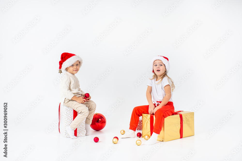 Happy little kids in Santa hat with Christmas gift boxes. Isolated on white background. Sale, holidays, christmas, new year, x-mas concept. Happy little kids in Santa hat with Christmas gift boxes. Isolated on white background. Sale, holidays, christmas, new year, x-mas concept.