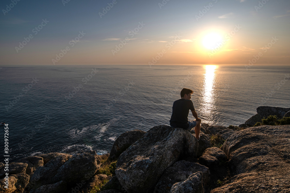 young boy relaxed in front of the sea in a sunset, holiday concept