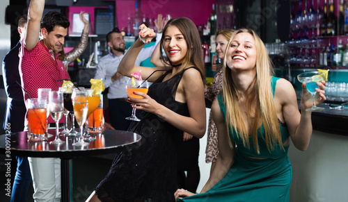 Portrait of smiling females and males having fun in the bar