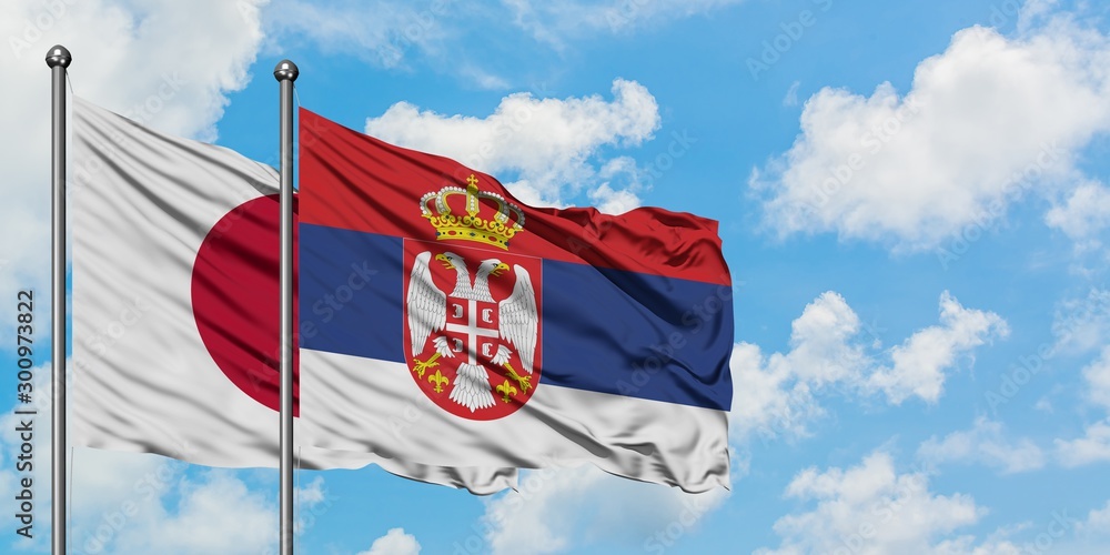 Japan and Serbia flag waving in the wind against white cloudy blue sky together. Diplomacy concept, international relations.