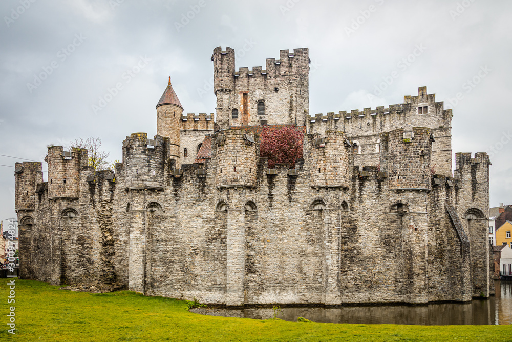 Fortified walls and towers of Gravensteen medieval castle with moat in the foreground, Ghent East Flanders, Belgium
