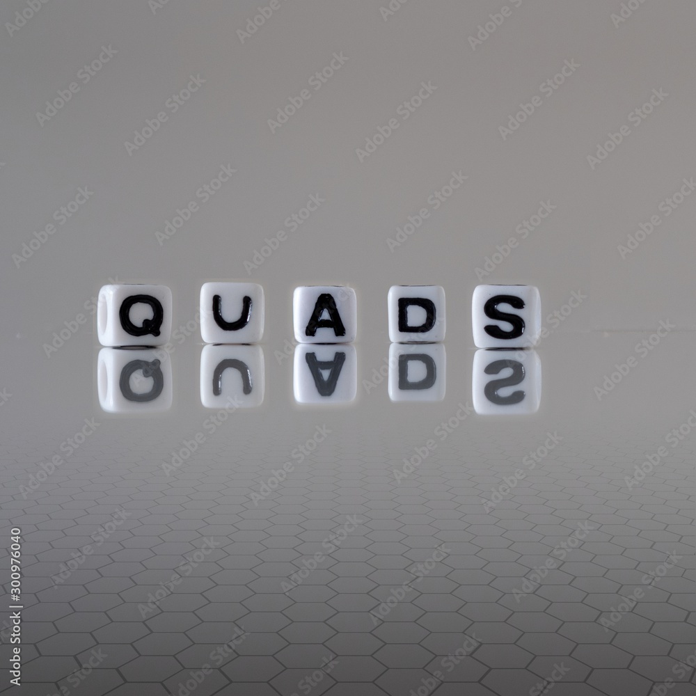 The concept of quads represented by wooden letter tiles The concept of quads represented by wooden letter tiles