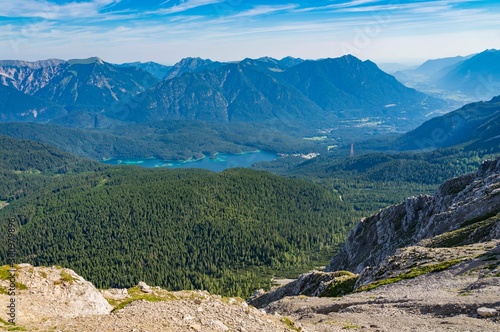 Alpine lake with mountain range and forest landscape on sunny summer day