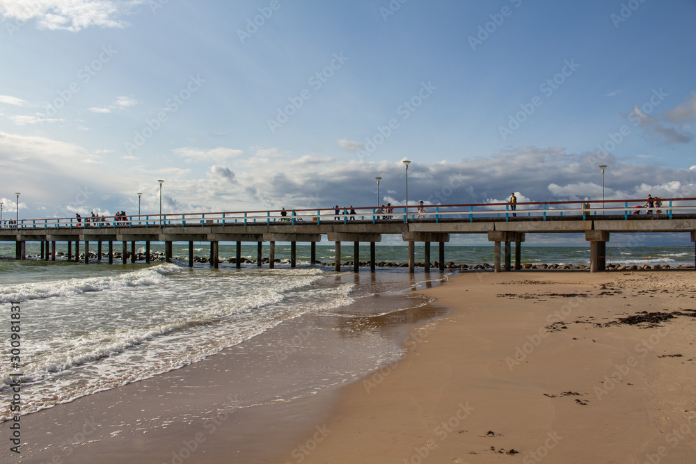 Fototapeta premium Sea Bridge in Palanga. Palanga Pier. Stormy Weather on the Beach. Green Waves. Stormy Sea. Dramatic Landscape With Stormy Sky And Waves. 