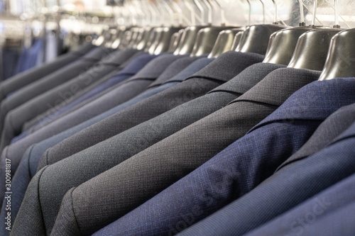 Men's jackets (suits) in blue and gray in a men's clothing store. Men's business suit