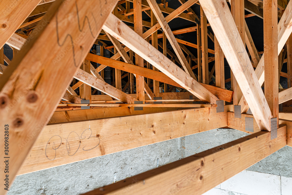 Roof trusses covered with a membrane on a detached house under construction, view from the inside, visible roof elements and truss plates. Roof trusses covered with a membrane on a detached house under construction, view from the inside, visible roof elements and truss plates.