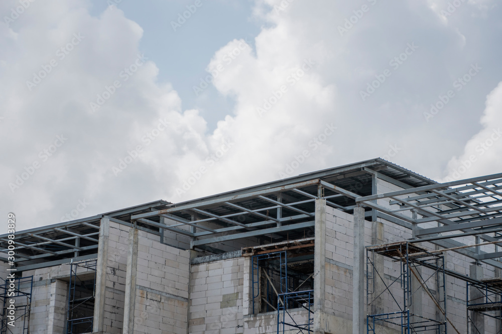 Building and Construction Site in progress. Building construction site against cloudy sky. Metal construction of unfinished building on construction of multi storage building. Building and Construction Site in progress. Building construction site against cloudy sky. Metal construction of unfinished building on construction of multi storage building.