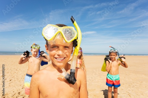 Boy in snorkeling mask, group of friends on beach