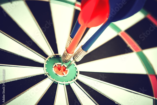 Dart arrow hitting in the target center of dartboard