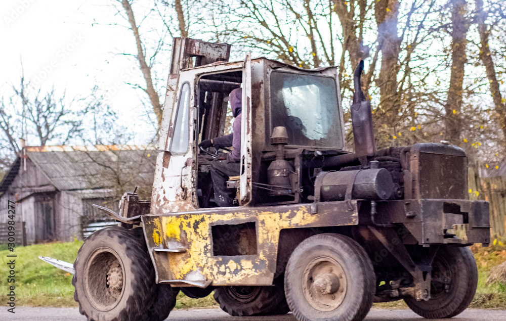 worker rides an old forklift, blue smoke comes from the chimney