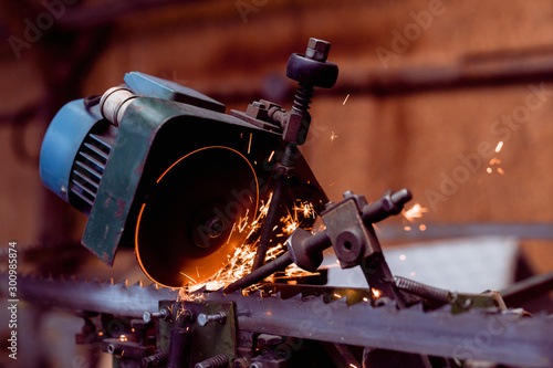 automatized old whetting machine, whet saw blade. close-up of freezed motion sparkle photo