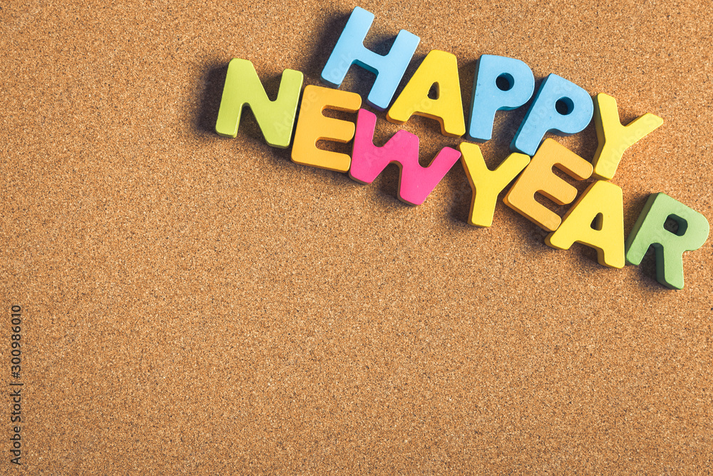 Happy New Year word formed by letter pieces on cork background Happy New Year word formed by letter pieces on cork background