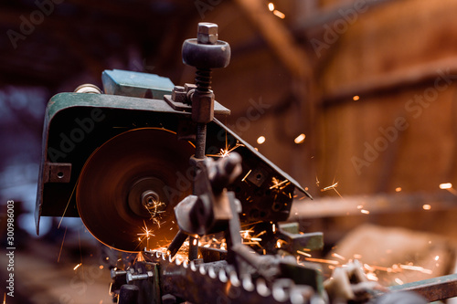 automatized old whetting machine, whet saw blade. close-up of freezed motion sparkle photo