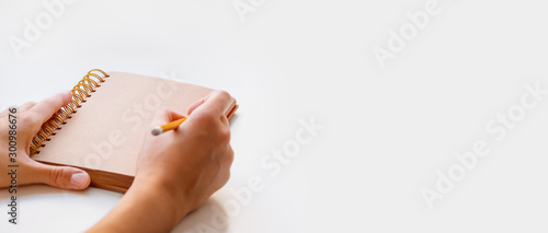 Woman is preparing to write or draw something in notepad with craft paper pages. Banner with copy space. photo