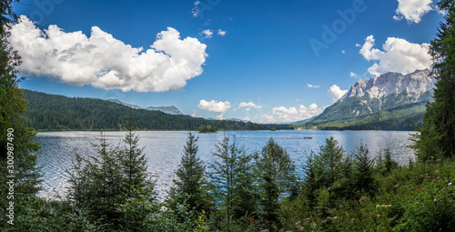 Alpine lake with mountain range and forest landscape on sunny summer day