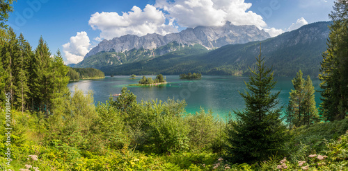 Alpine lake with mountain range and forest landscape on sunny summer day
