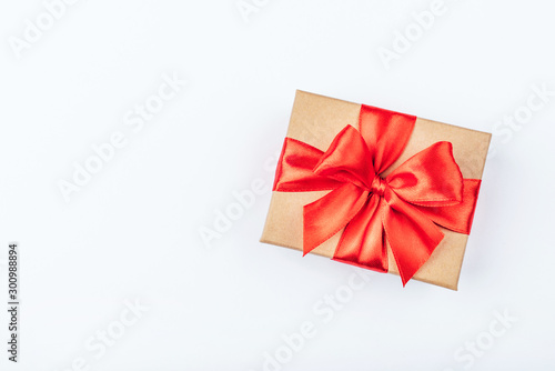 Cardboard gift box with red bow on white background. Flat lay. Top view. Copy space for your text.