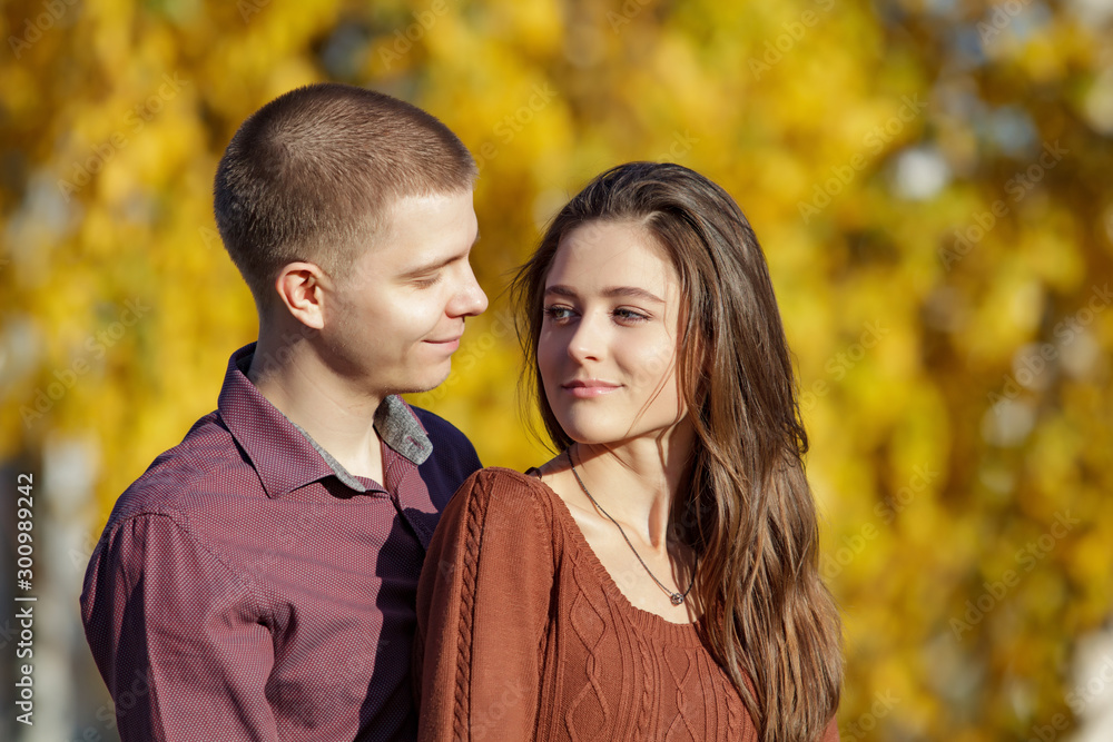 Fototapeta premium Beautiful young couple in orange autumn leave. Handsome man and attractive woman, love story in autumn park. People relationships.